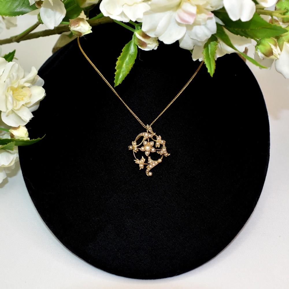An Edwardian 15ct yellow gold floral brooch pendant featuring openwork scrollwork set with seed pearls. View IX