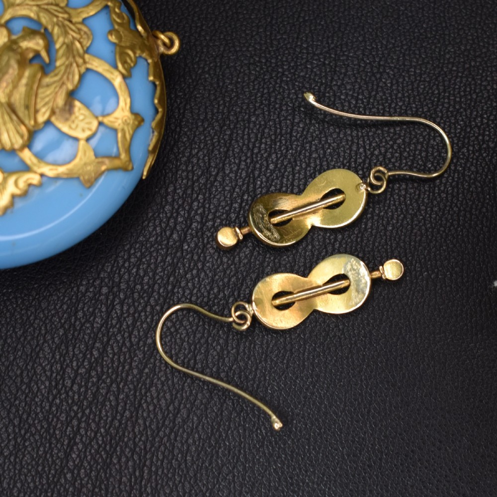 A pair of Edwardian gold drop earrings featuring figure-eight infinity loops set with seed pearls, displayed inside a blue velvet presentation box. View VII