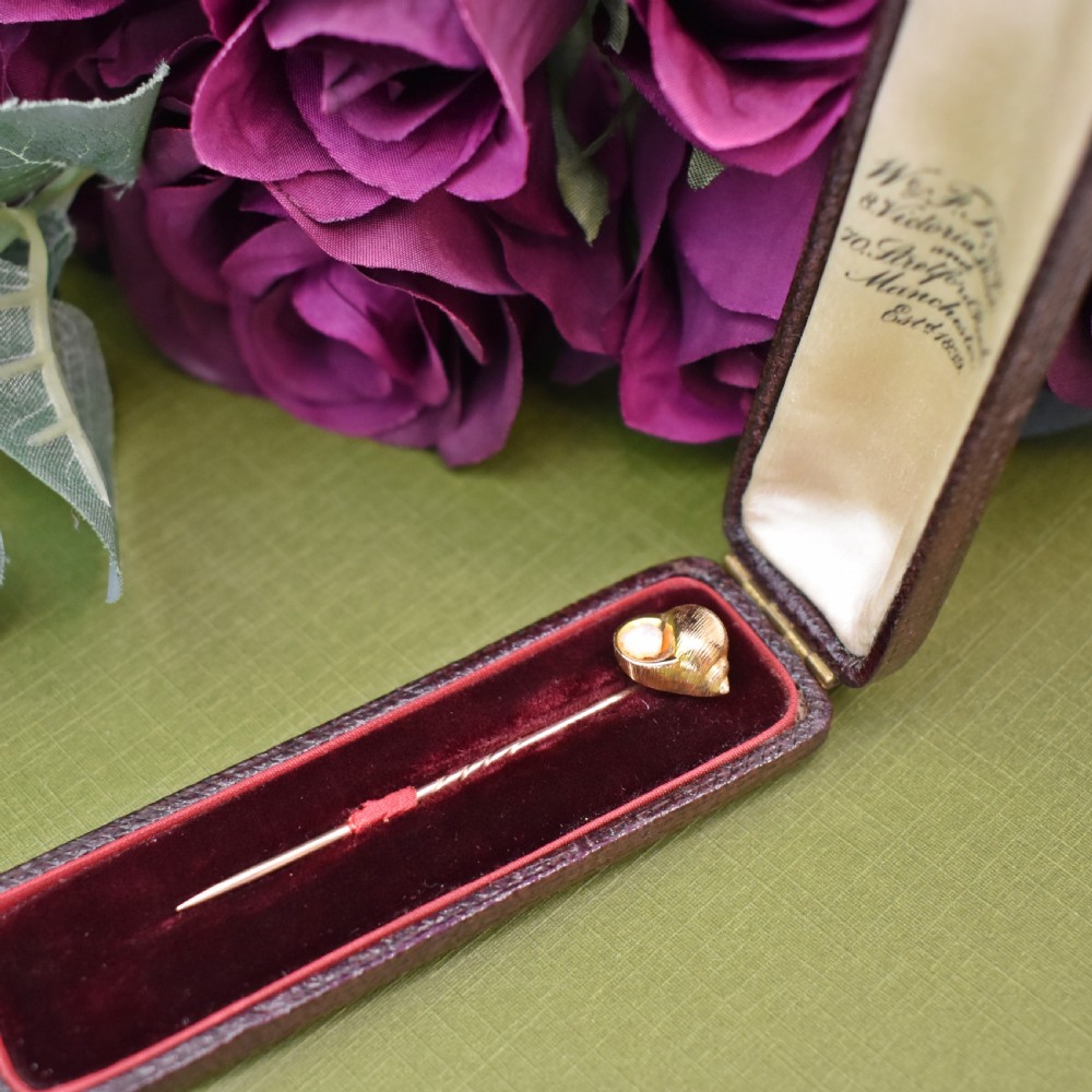 An Edwardian yellow gold stick pin featuring a textured shell casing enclosing a natural baroque pearl. View III