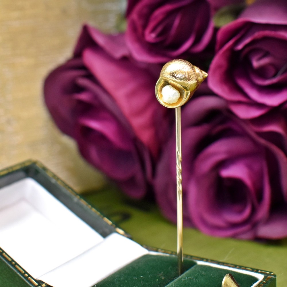 An Edwardian yellow gold stick pin featuring a textured shell casing enclosing a natural baroque pearl. View IV