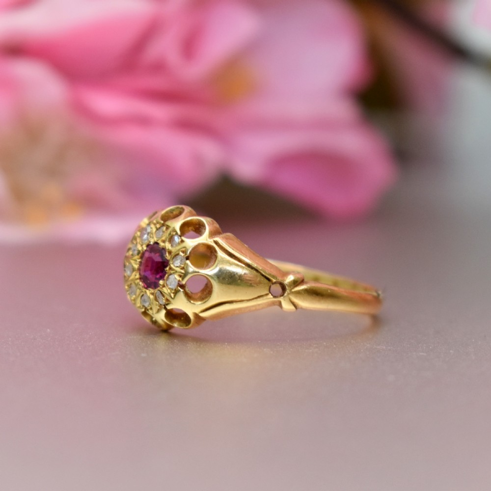 An 18ct yellow gold Edwardian ring featuring a central round ruby encircled by diamond accents set into a carved head band. View III