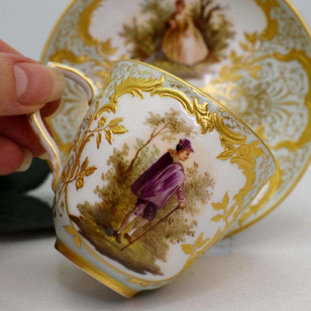 A nineteenth-century KPM Berlin porcelain teacup and matching saucer featuring gilded relief scrollwork and hand-painted figures in a landscape. View VI