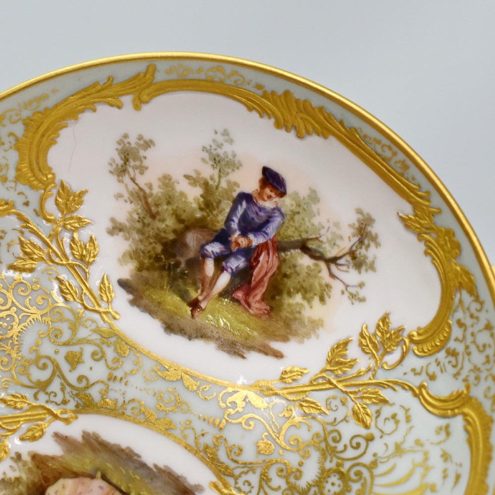 A nineteenth-century KPM Berlin porcelain teacup and matching saucer featuring gilded relief scrollwork and hand-painted figures in a landscape. View IX