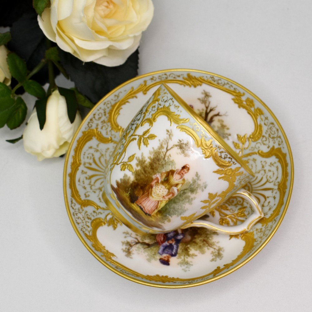 A nineteenth-century KPM Berlin porcelain teacup and matching saucer featuring gilded relief scrollwork and hand-painted figures in a landscape. View XII
