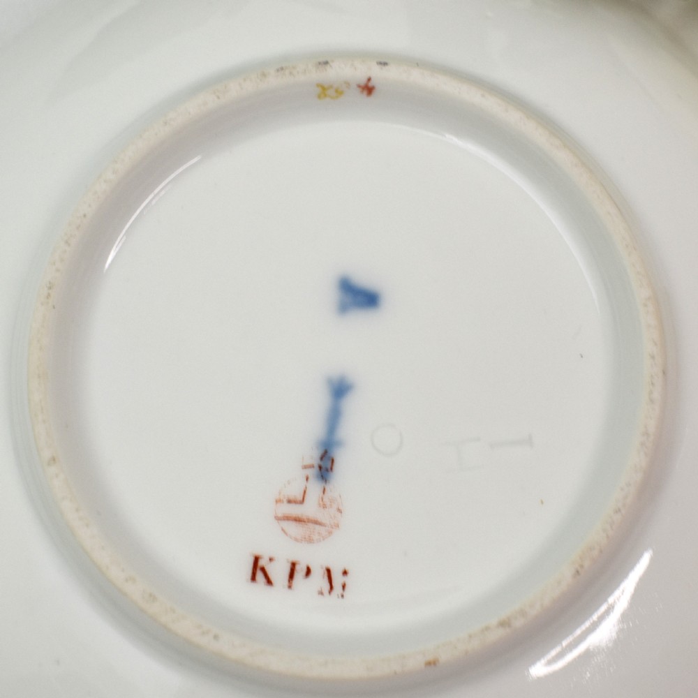 A nineteenth-century KPM Berlin porcelain teacup and matching saucer featuring gilded relief scrollwork and hand-painted figures in a landscape. View XIV
