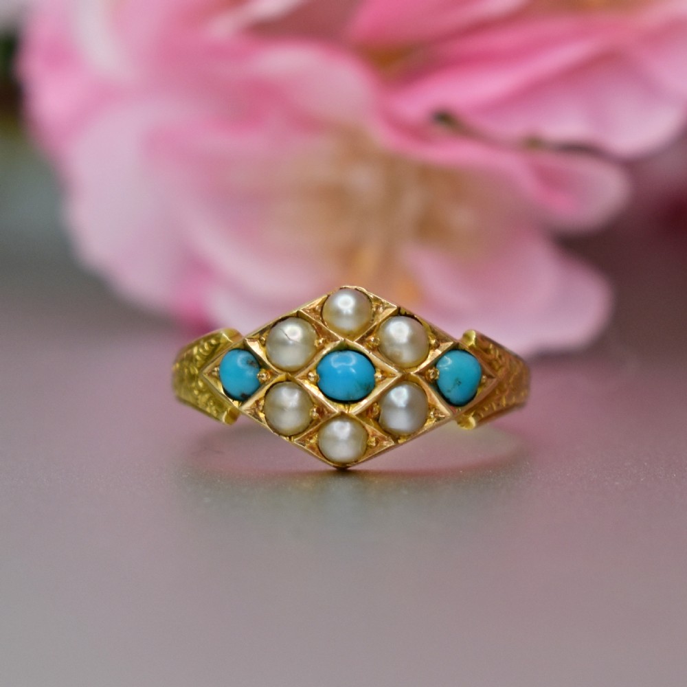 A late Victorian 15ct yellow gold ring featuring a diamond-shaped face set with turquoise cabochons and split pearls, flanked by engraved shoulders. View II