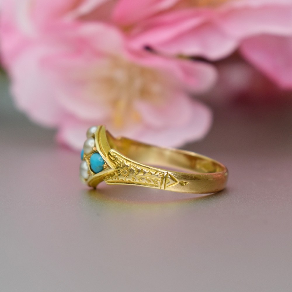 A late Victorian 15ct yellow gold ring featuring a diamond-shaped face set with turquoise cabochons and split pearls, flanked by engraved shoulders. View V