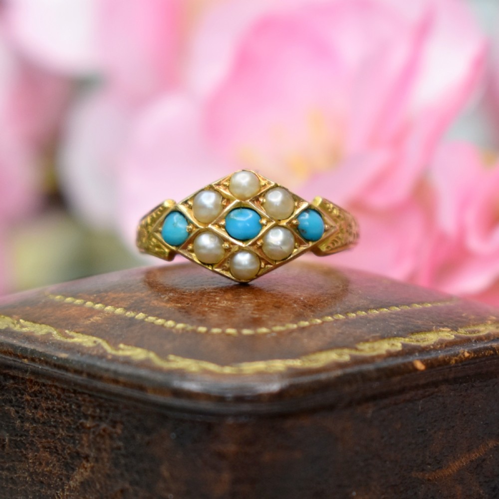A late Victorian 15ct yellow gold ring featuring a diamond-shaped face set with turquoise cabochons and split pearls, flanked by engraved shoulders. View VI