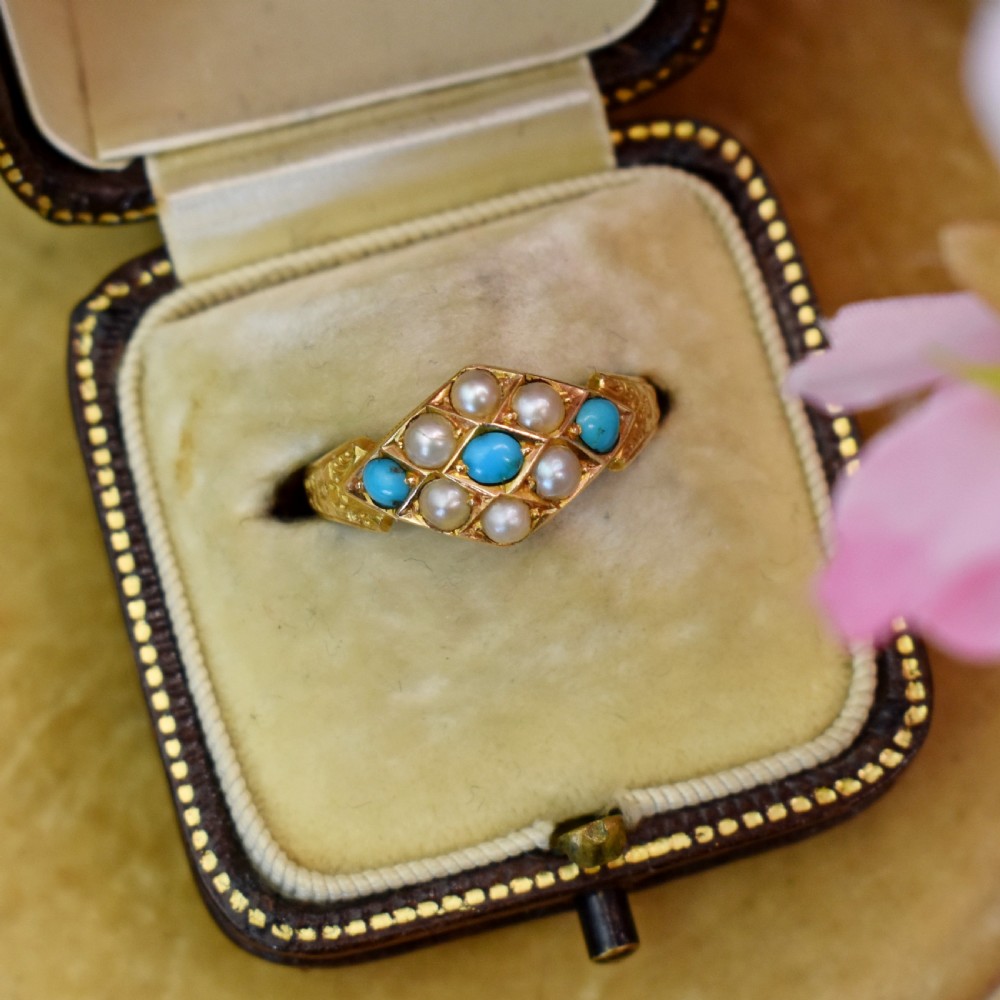 A late Victorian 15ct yellow gold ring featuring a diamond-shaped face set with turquoise cabochons and split pearls, flanked by engraved shoulders. View VII