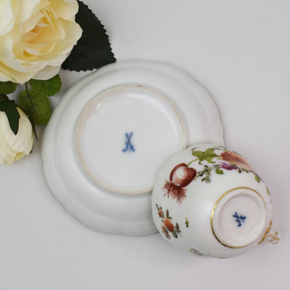 A white porcelain demitasse cup and matching saucer painted with polychrome floral sprays and finished with gold gilded scalloped edges. View XII