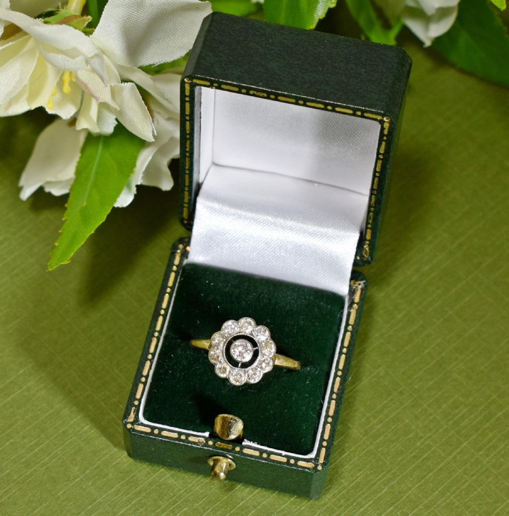 An Art Deco target ring featuring a central round diamond surrounded by a black ring and a scalloped outer border of diamonds set on an 18ct gold band.