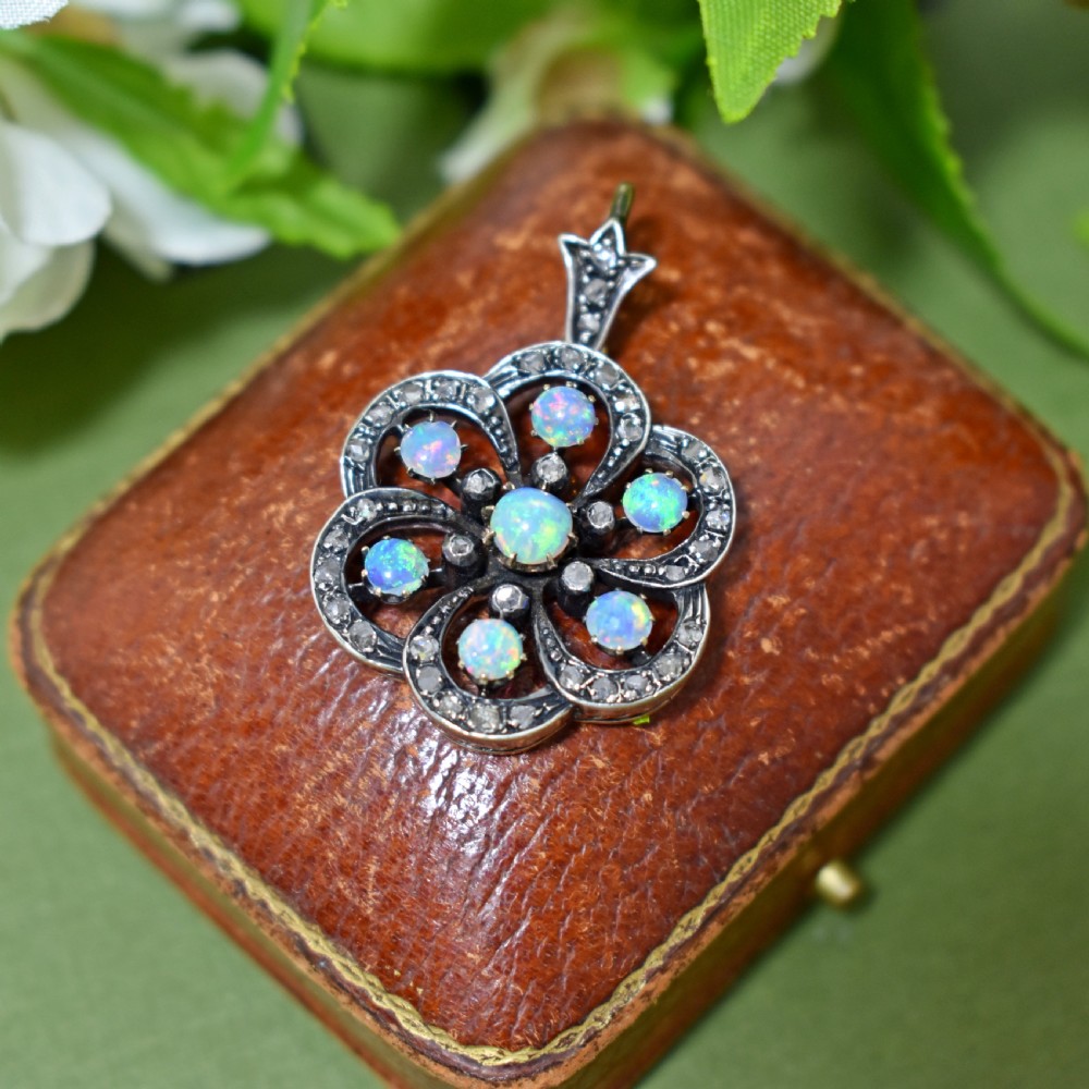 A late Victorian openwork floral pendant crafted from silver-topped gold, set with central and surrounding cabochon opals bordered by rose-cut diamonds.