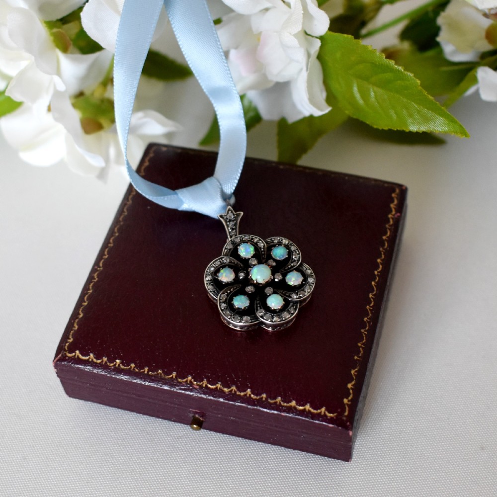 A late Victorian openwork floral pendant crafted from silver-topped gold, set with central and surrounding cabochon opals bordered by rose-cut diamonds. View V