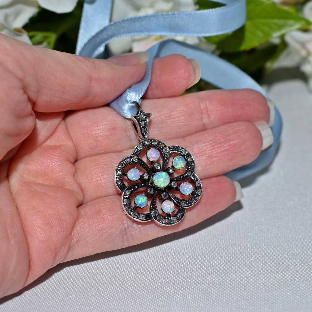 A late Victorian openwork floral pendant crafted from silver-topped gold, set with central and surrounding cabochon opals bordered by rose-cut diamonds. View VII