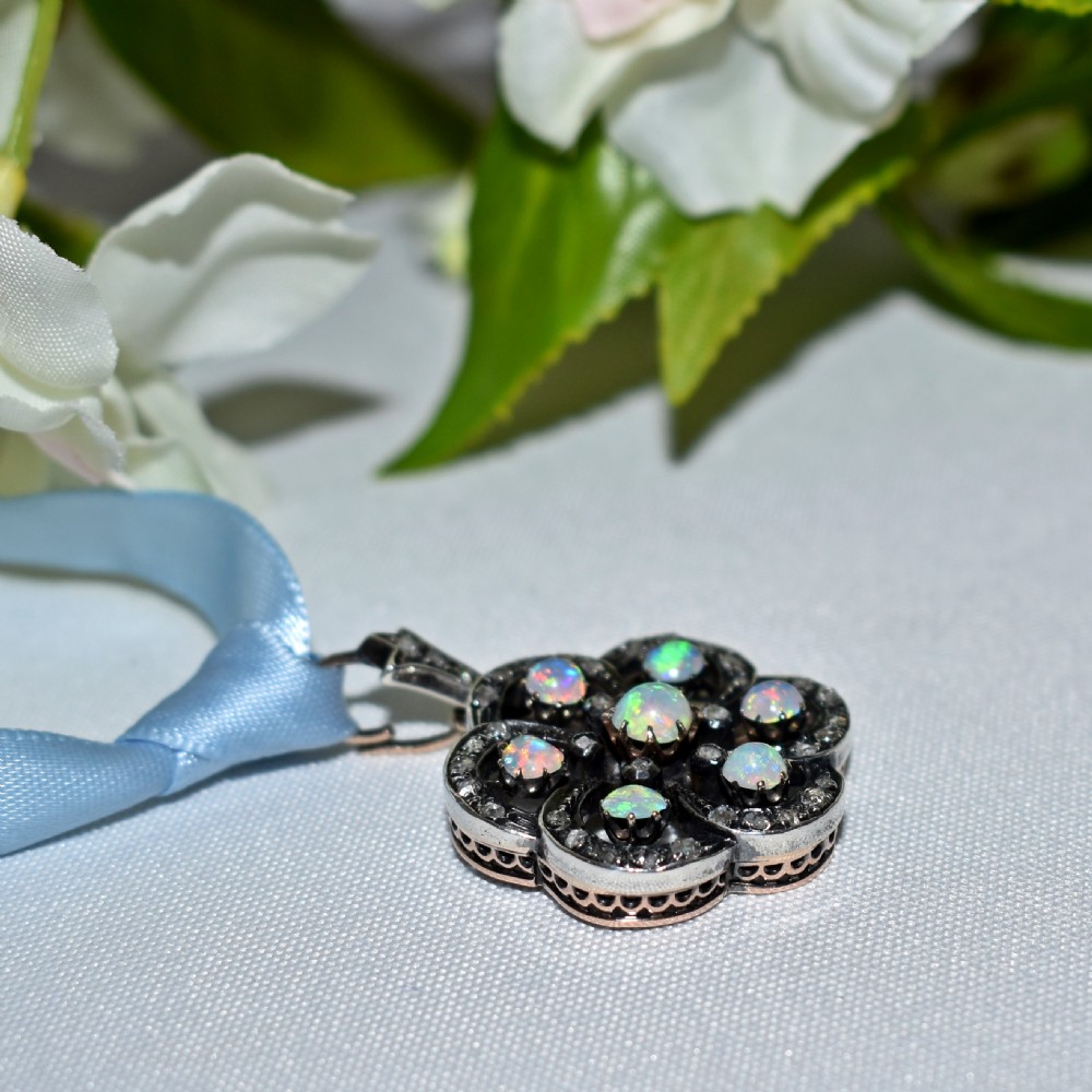 A late Victorian openwork floral pendant crafted from silver-topped gold, set with central and surrounding cabochon opals bordered by rose-cut diamonds. View VIII