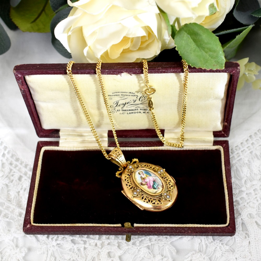 An oval 18ct gold Victorian locket pendant featuring a hand-painted enamel miniature of a figure surrounded by filigree work and seed pearls on a gold chain. View V