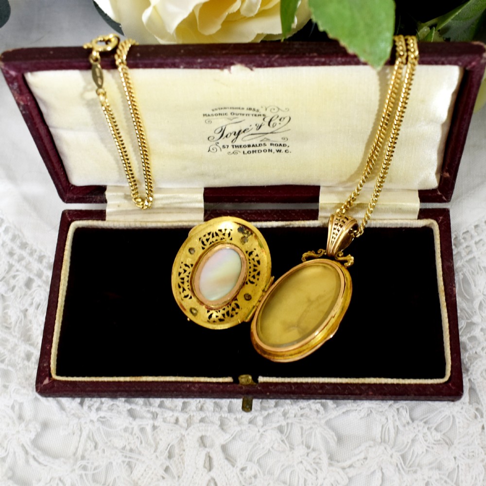 An oval 18ct gold Victorian locket pendant featuring a hand-painted enamel miniature of a figure surrounded by filigree work and seed pearls on a gold chain. View VI