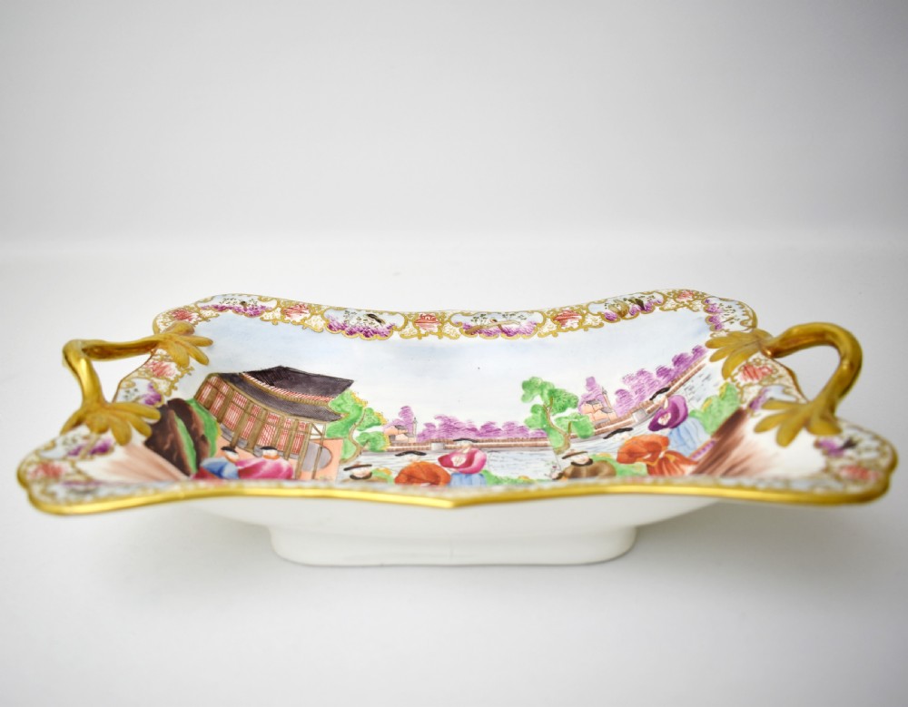 A Regency-era rectangular Swansea porcelain comport featuring gilded twin handles, a shaped border, and a polychrome hand-painted Mandarin Chinoiserie landscape scene. View IX