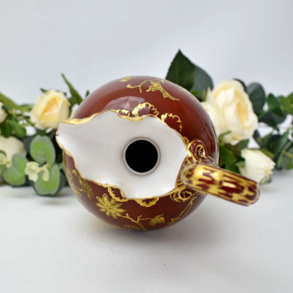 A Victorian Royal Crown Derby porcelain ewer with a terracotta brown ground, single loop handle, flared spout, and raised gold floral gilding on a square pedestal base. View VII