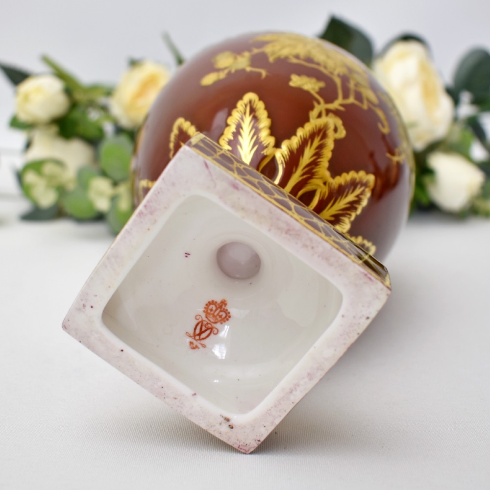 A Victorian Royal Crown Derby porcelain ewer with a terracotta brown ground, single loop handle, flared spout, and raised gold floral gilding on a square pedestal base. View XI