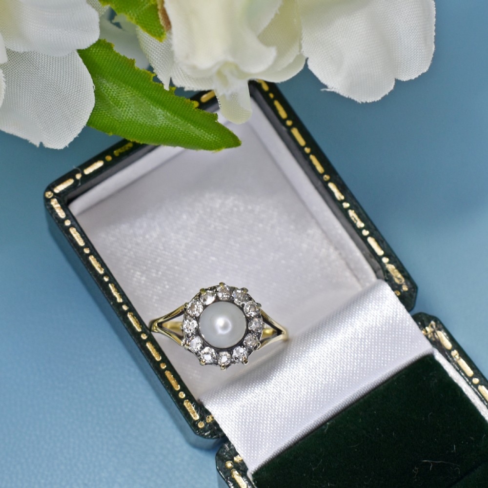 An Edwardian 18ct yellow gold cluster ring featuring a central white pearl surrounded by a halo of old cut diamonds with split shoulders. View VIII