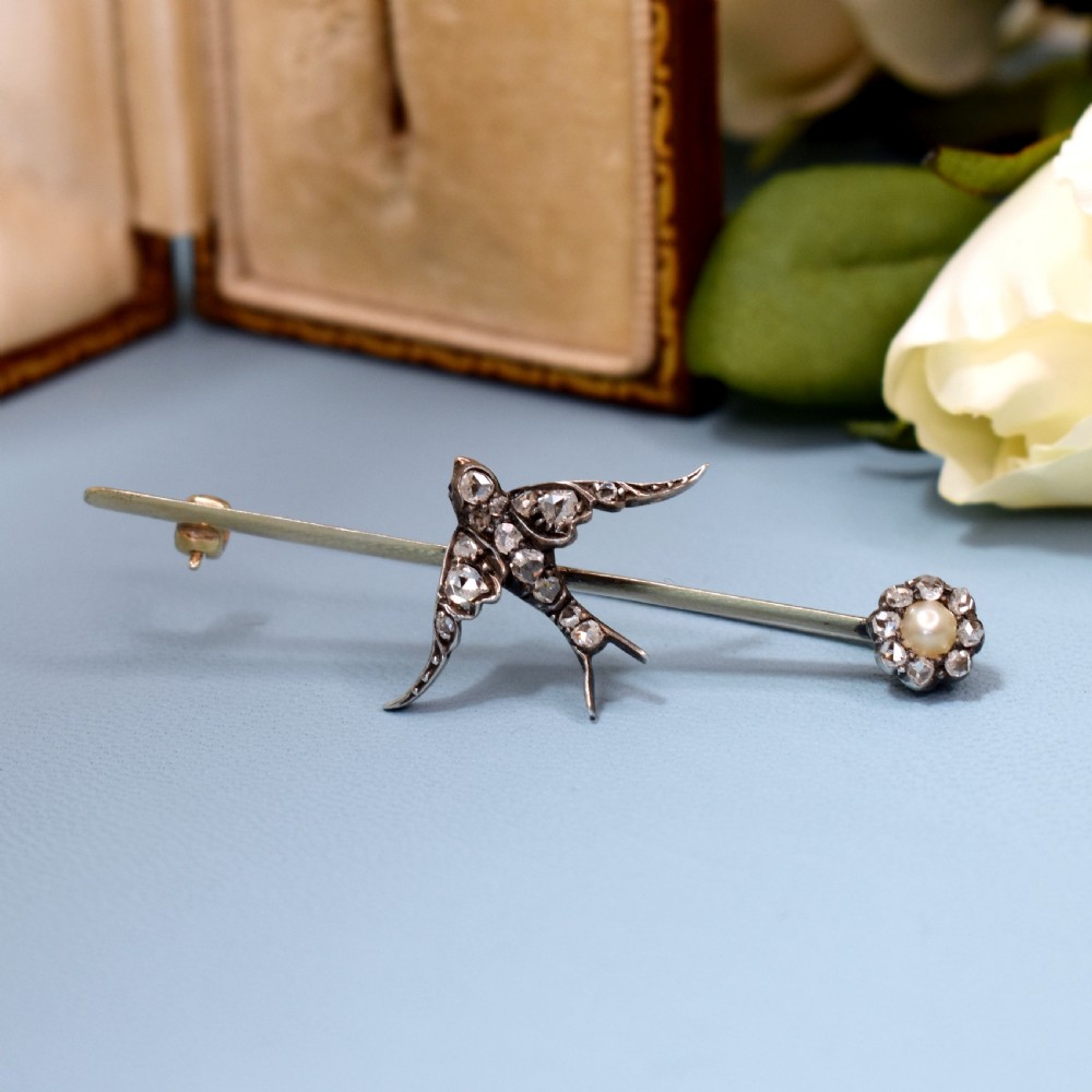 An Edwardian 15ct gold bar brooch featuring a silver-topped swallow in flight set with rose-cut diamonds beside a pearl cluster. View III