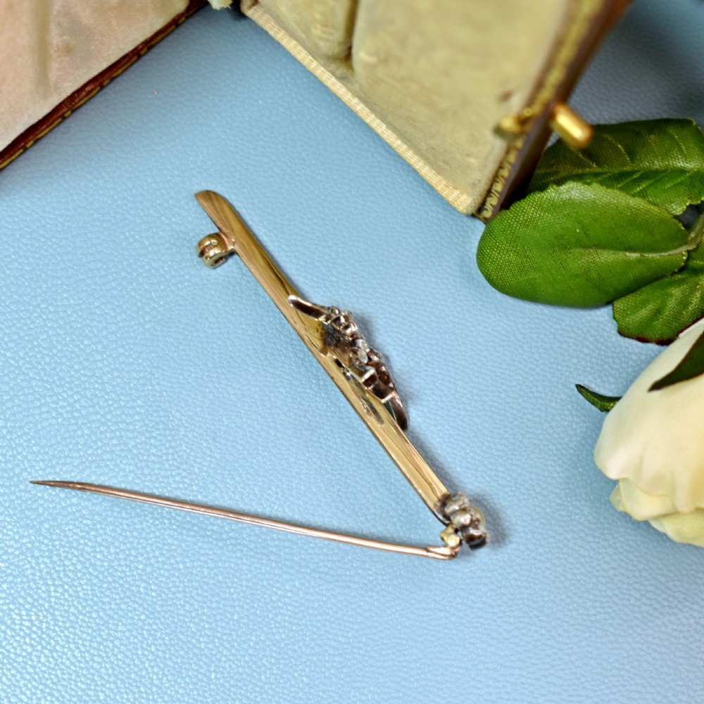 An Edwardian 15ct gold bar brooch featuring a silver-topped swallow in flight set with rose-cut diamonds beside a pearl cluster. View VIII