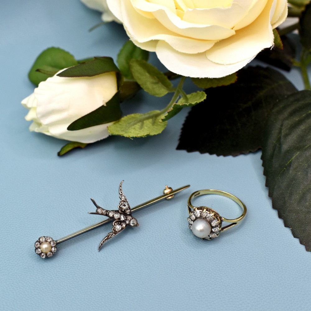 An Edwardian 15ct gold bar brooch featuring a silver-topped swallow in flight set with rose-cut diamonds beside a pearl cluster. View XI