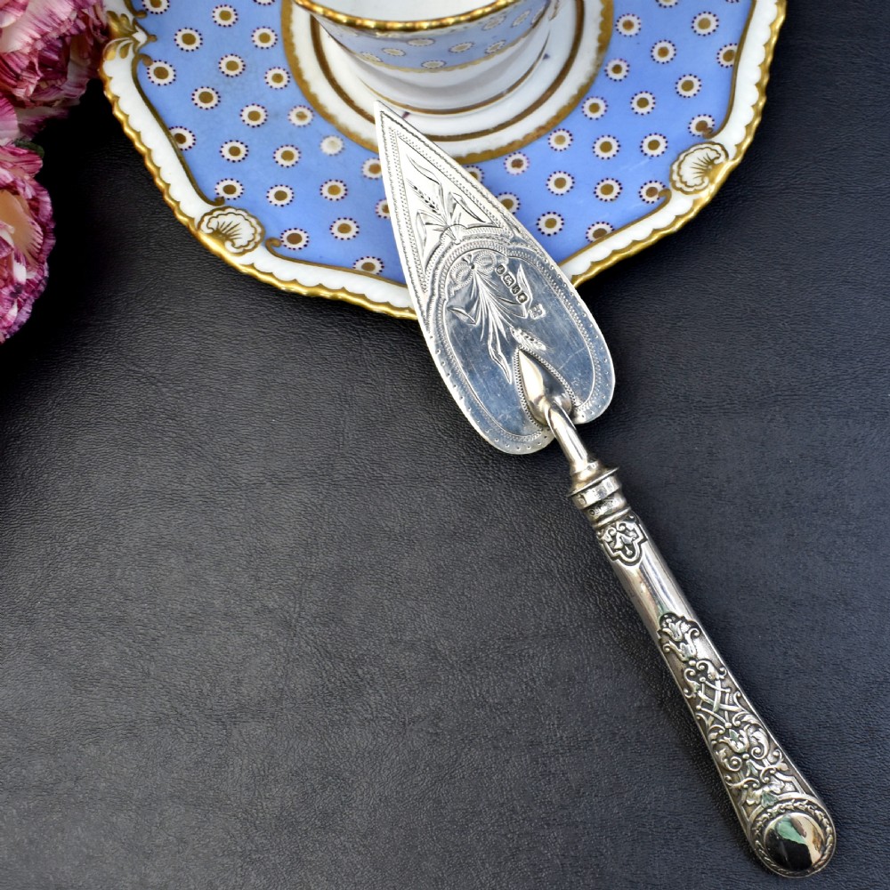 A Victorian sterling silver pastry server with a pointed trowel-shaped blade engraved with floral motifs and an ornate relief handle. View II