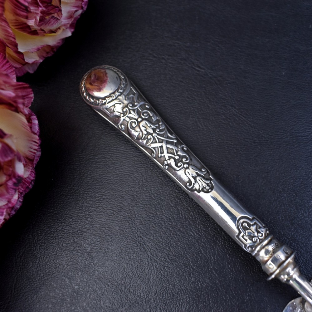A Victorian sterling silver pastry server with a pointed trowel-shaped blade engraved with floral motifs and an ornate relief handle. View V