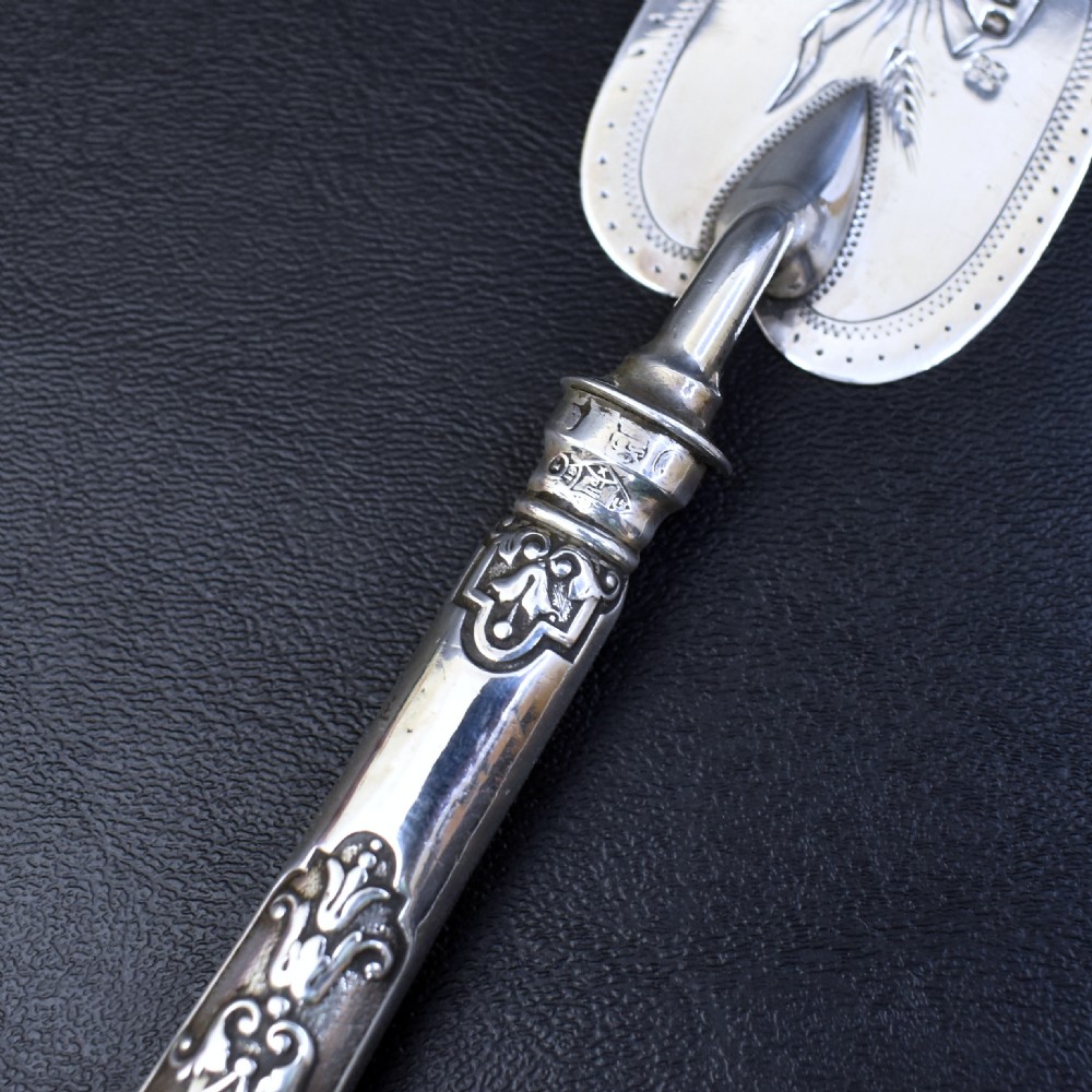 A Victorian sterling silver pastry server with a pointed trowel-shaped blade engraved with floral motifs and an ornate relief handle. View VII