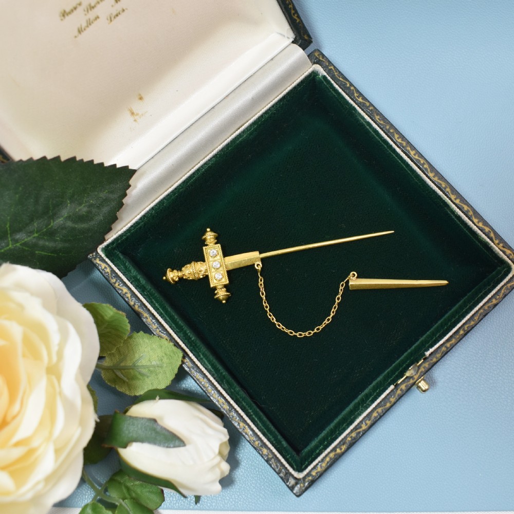 A Victorian 18 carat gold jabot pin crafted in the shape of a sword, featuring three old-cut diamonds set along the guard, cannetille wirework, and a safety chain. View III
