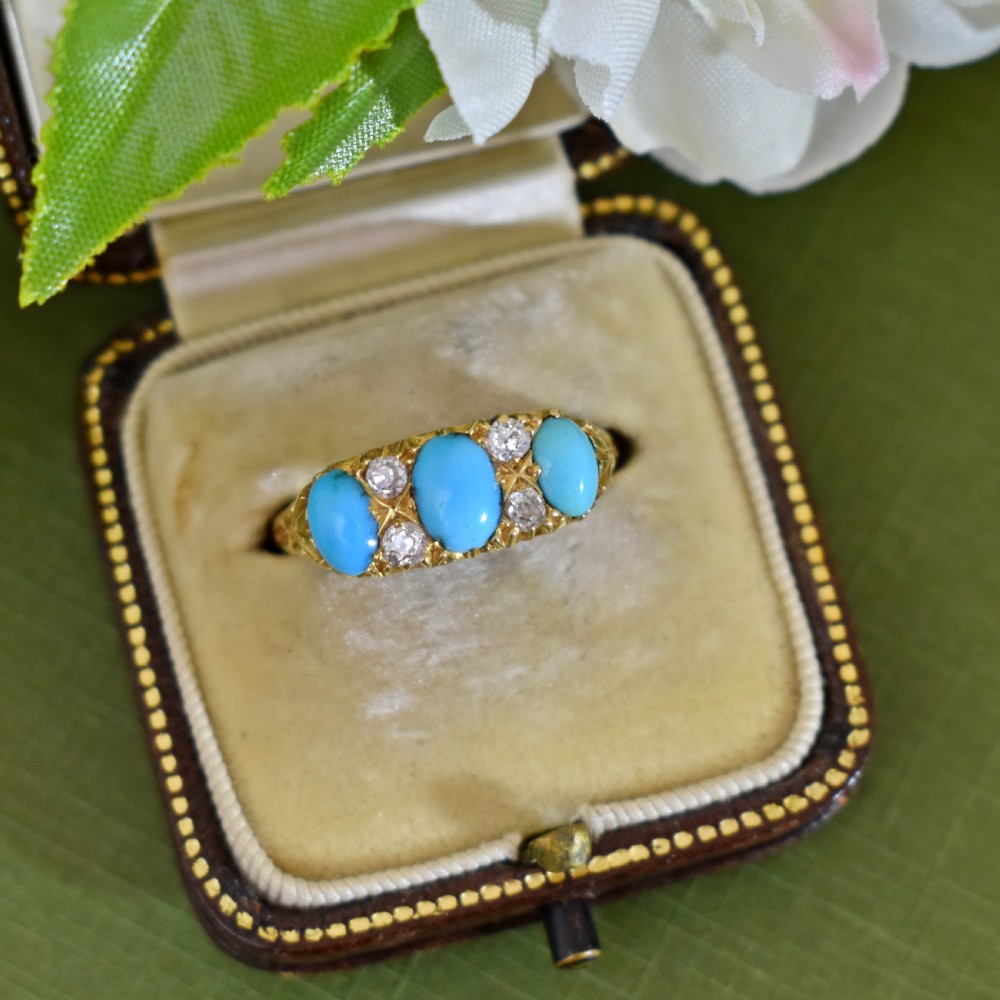 A Victorian 18ct gold ring featuring three oval turquoise cabochons separated by four accent diamonds in a carved band.