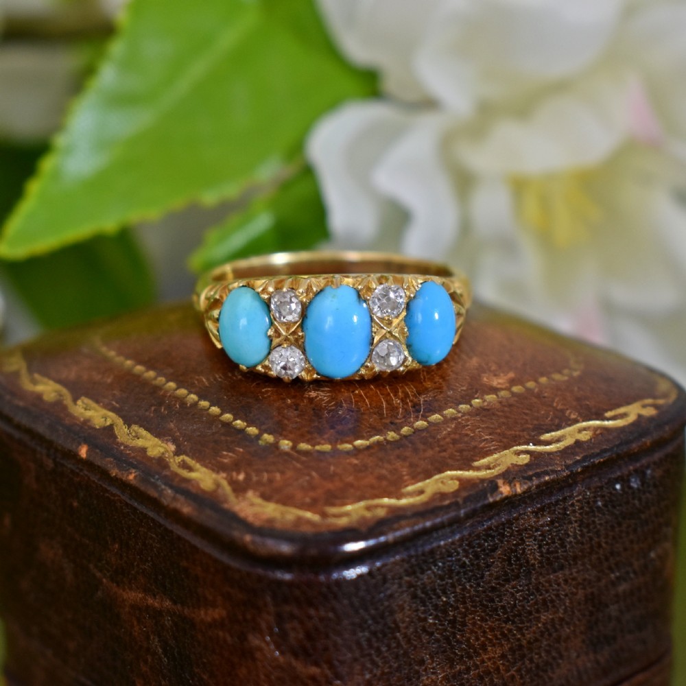 A Victorian 18ct gold ring featuring three oval turquoise cabochons separated by four accent diamonds in a carved band. View II