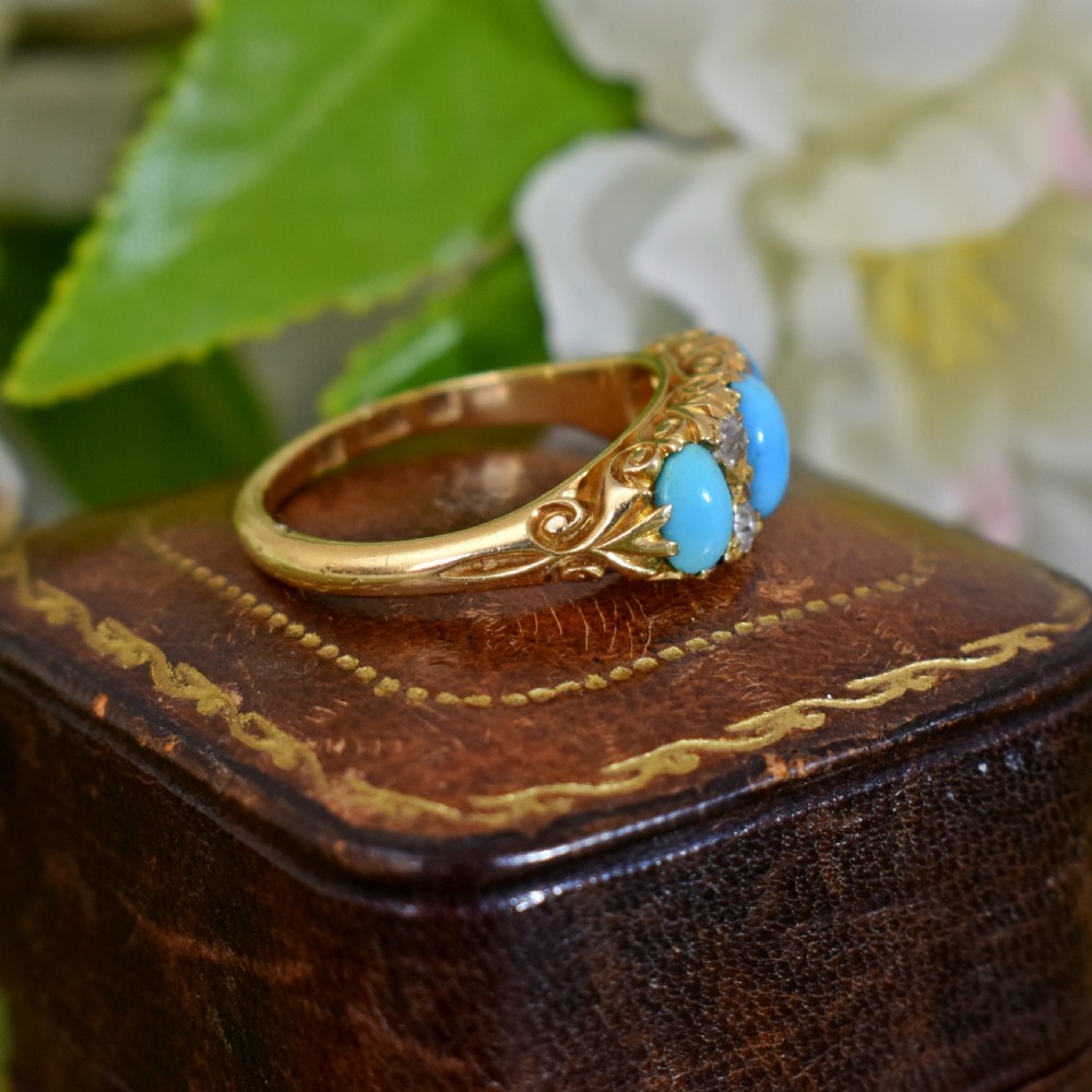 A Victorian 18ct gold ring featuring three oval turquoise cabochons separated by four accent diamonds in a carved band. View III