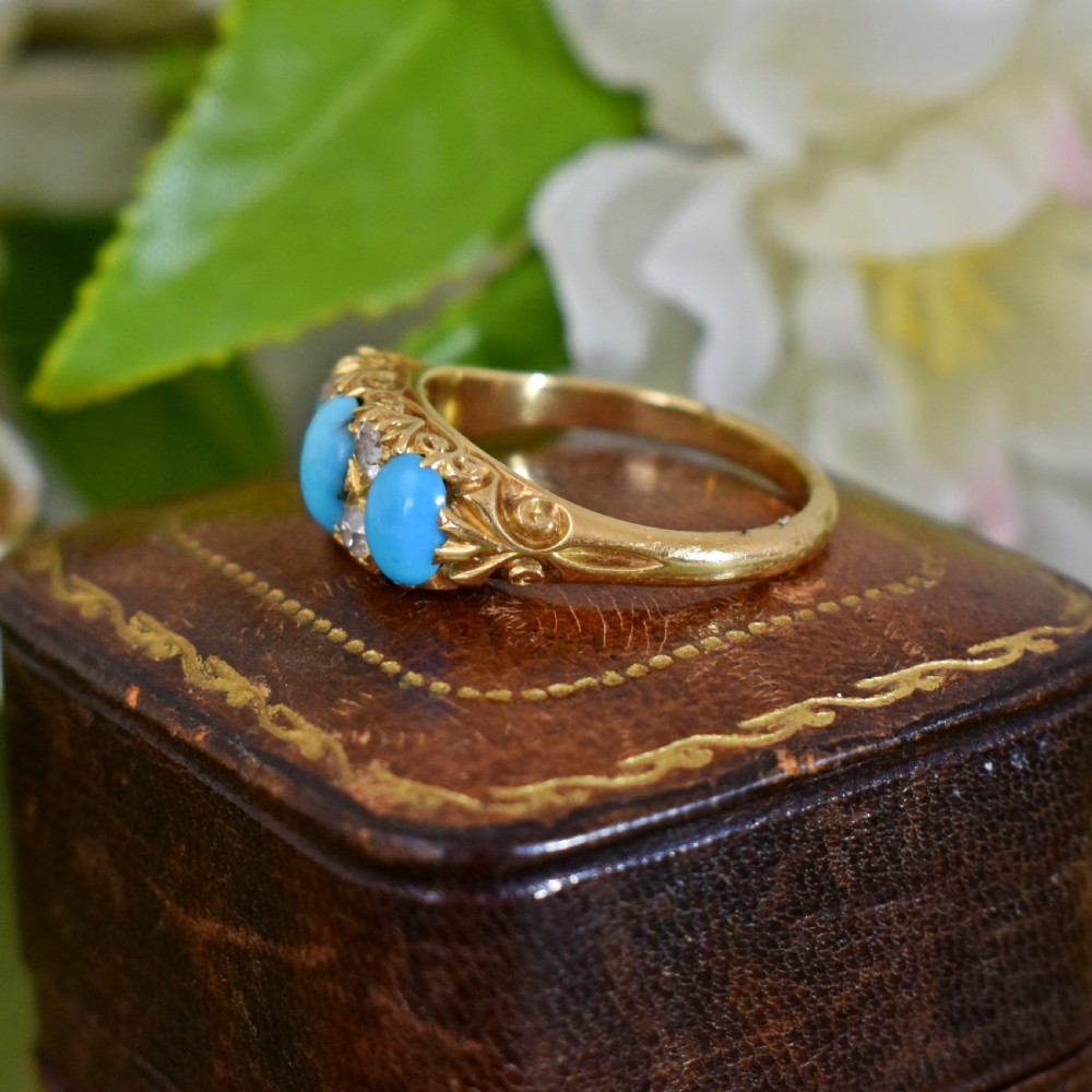 A Victorian 18ct gold ring featuring three oval turquoise cabochons separated by four accent diamonds in a carved band. View IV
