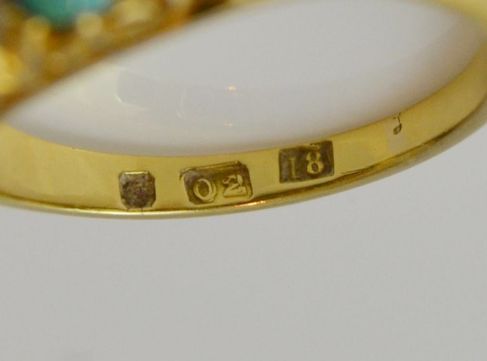 A Victorian 18ct gold ring featuring three oval turquoise cabochons separated by four accent diamonds in a carved band. View X
