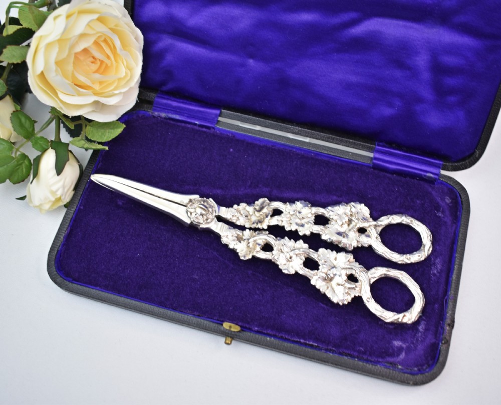 A pair of solid sterling silver grape scissors featuring heavily detailed cast grapevine handles with circular finger loops and tapered blades. View II