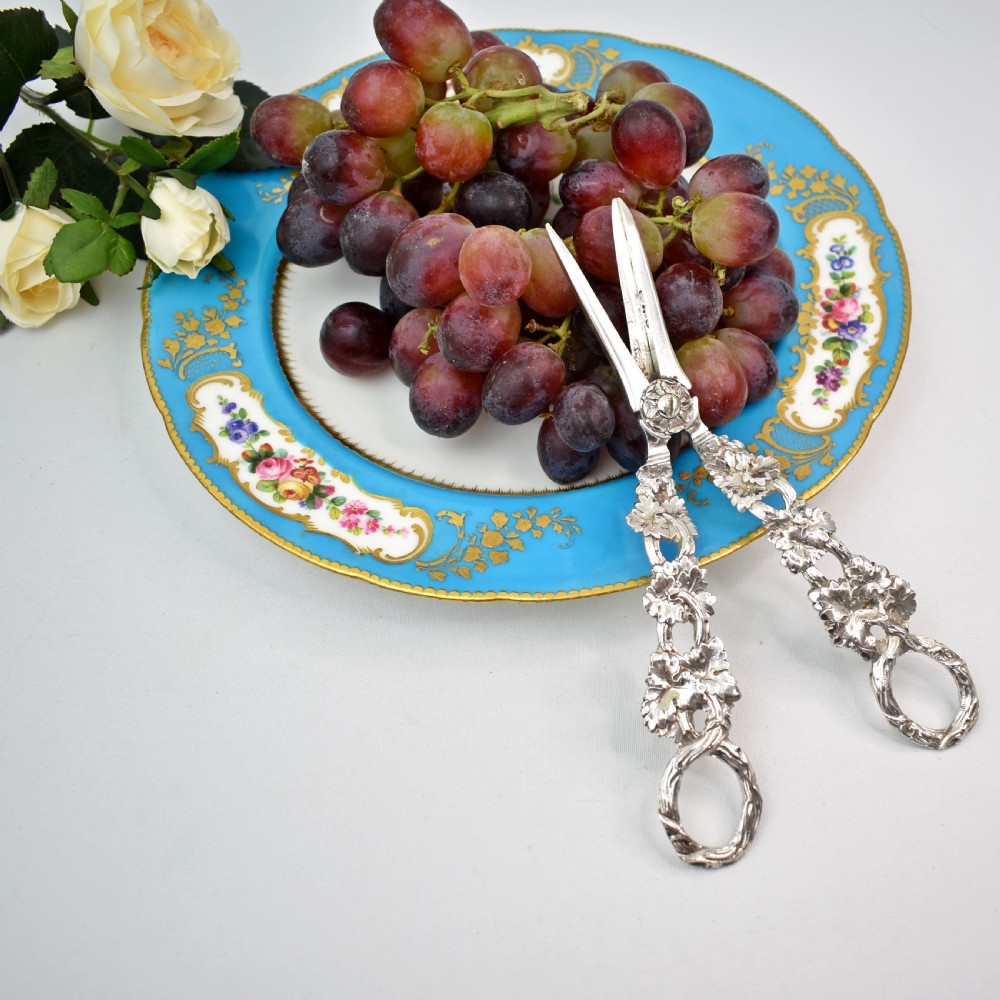 A pair of solid sterling silver grape scissors featuring heavily detailed cast grapevine handles with circular finger loops and tapered blades. View IV