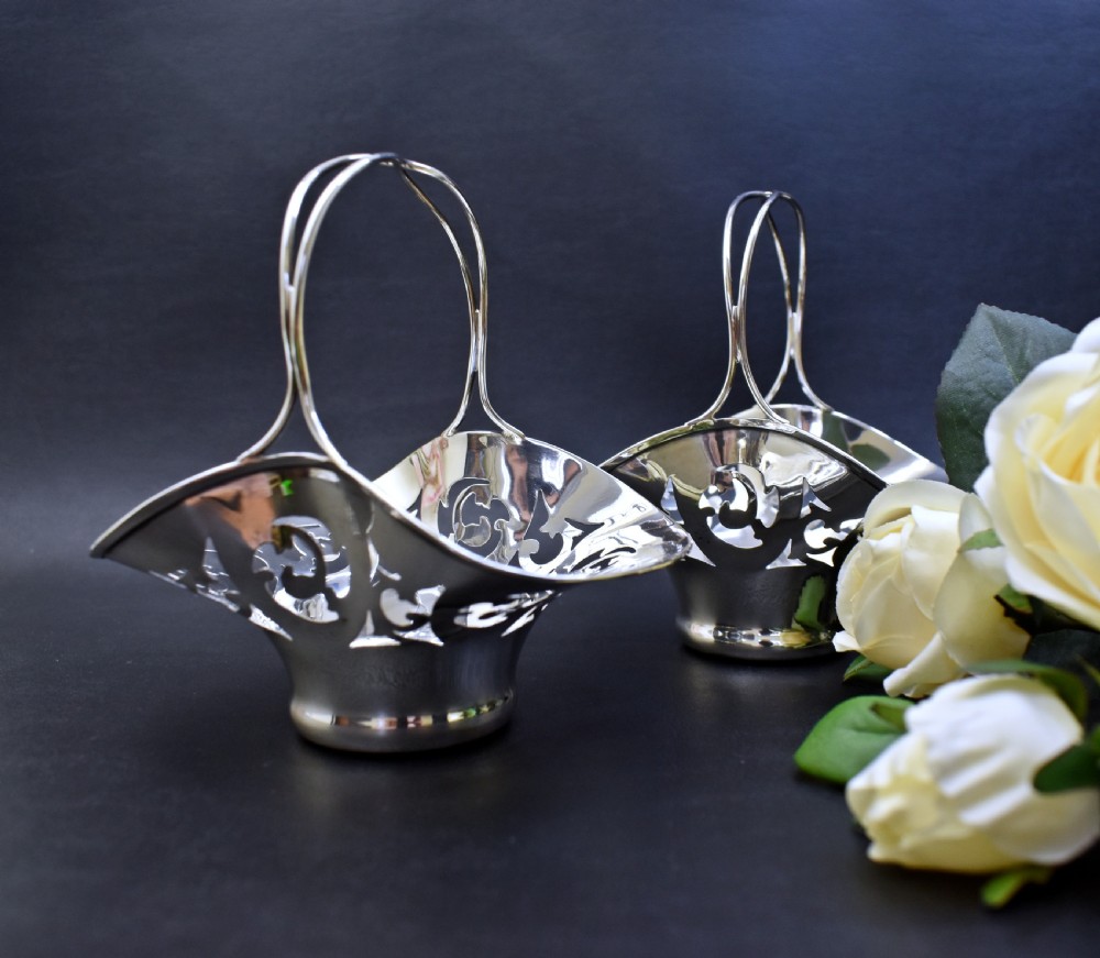 A pair of polished sterling silver bonbon baskets featuring pierced scrollwork patterns and high looped handles. View III