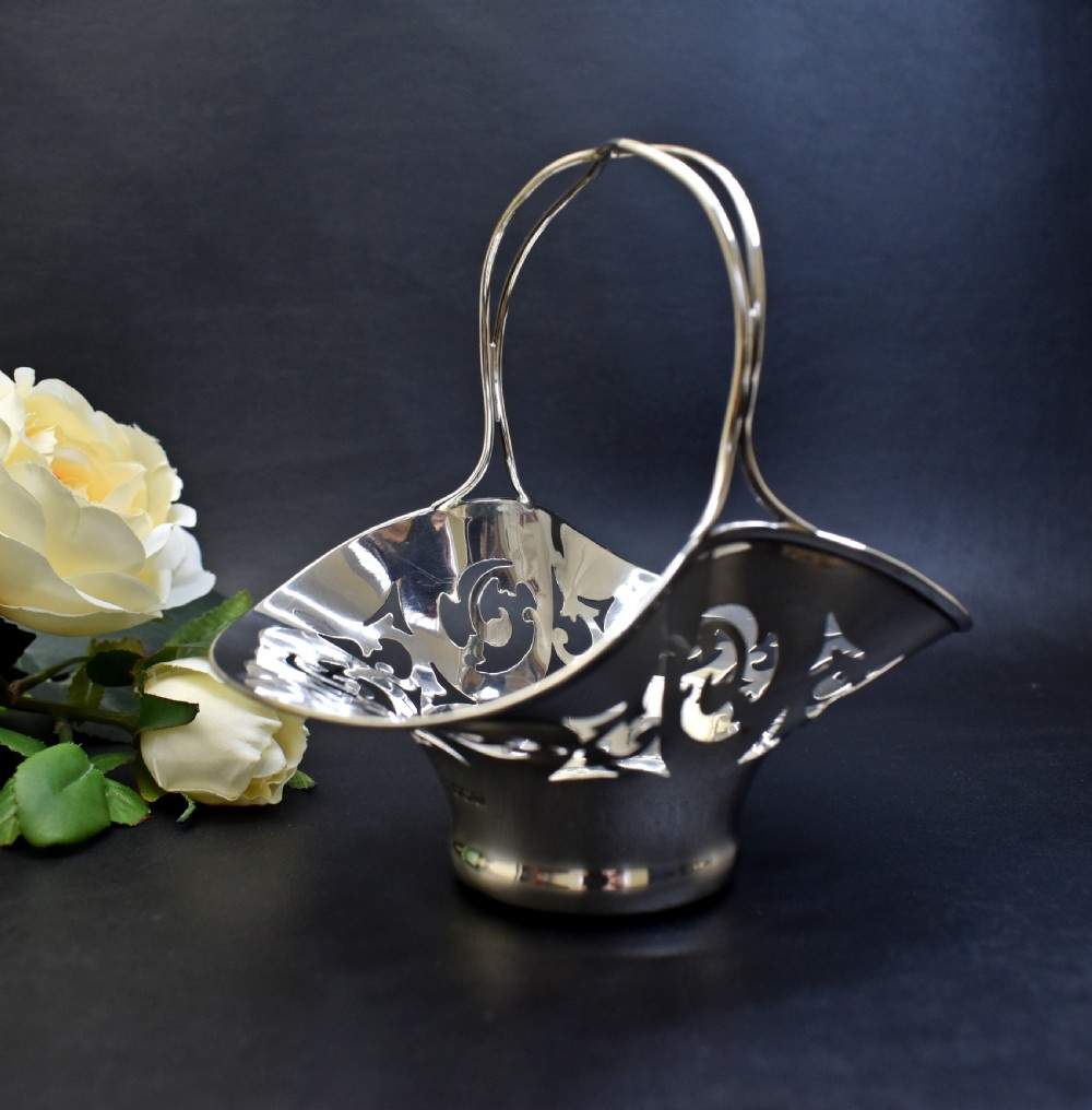 A pair of polished sterling silver bonbon baskets featuring pierced scrollwork patterns and high looped handles. View V