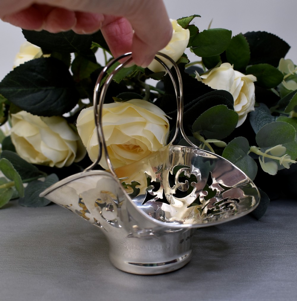 A pair of polished sterling silver bonbon baskets featuring pierced scrollwork patterns and high looped handles. View VII