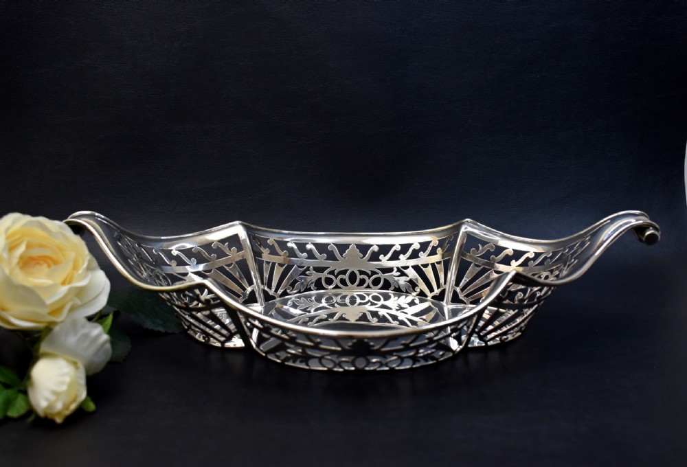A sterling silver bread basket featuring pierced fretwork sides and swept scroll handles at both ends. View II