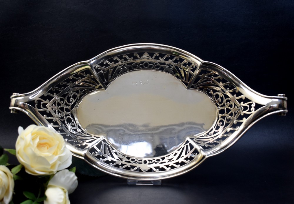 A sterling silver bread basket featuring pierced fretwork sides and swept scroll handles at both ends. View III