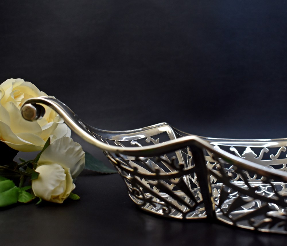 A sterling silver bread basket featuring pierced fretwork sides and swept scroll handles at both ends. View V