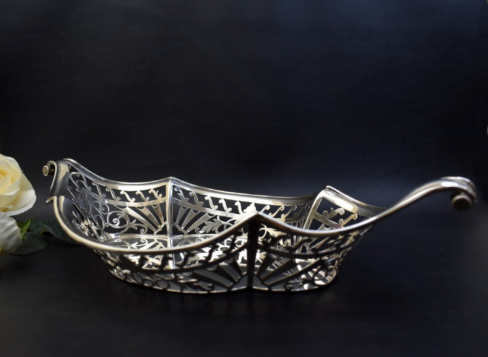 A sterling silver bread basket featuring pierced fretwork sides and swept scroll handles at both ends. View VII