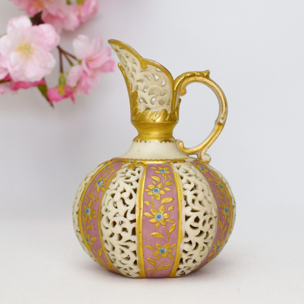 A late Victorian Grainger Worcester reticulated porcelain ewer featuring pink floral panels alternating with lattice pierced work and gilded accents.