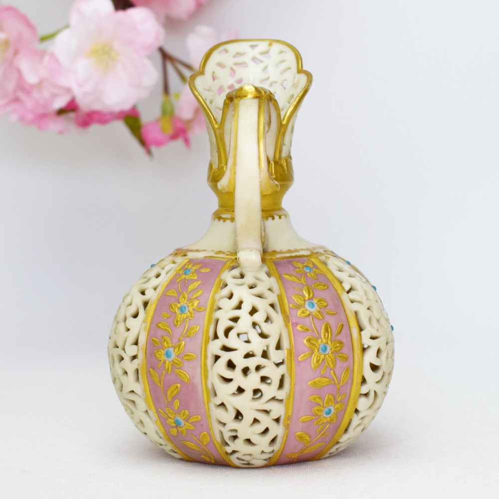 A late Victorian Grainger Worcester reticulated porcelain ewer featuring pink floral panels alternating with lattice pierced work and gilded accents. View IV