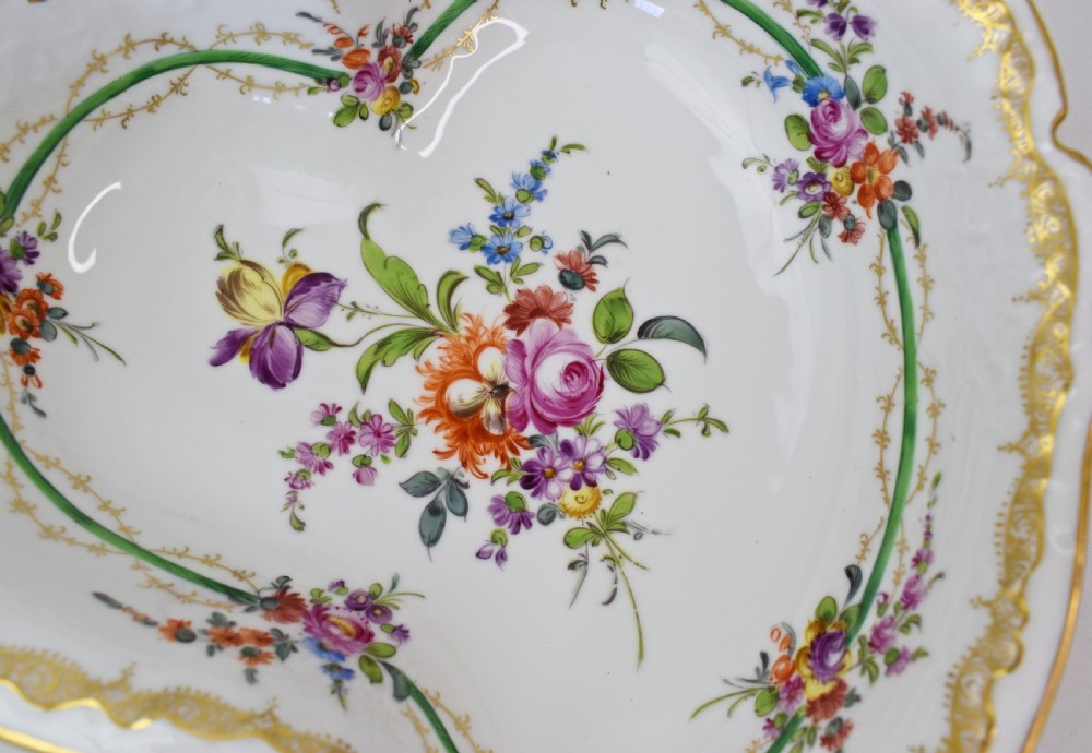 A white Rococo-style porcelain dish adorned with hand-painted floral sprays, a green inner rim, and a gilded scroll handle. View V