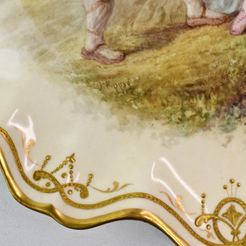 A circular Victorian porcelain cabinet plate featuring a hand-painted romantic pastoral scene enclosed by a lobed rim decorated with gold gilding. View VII